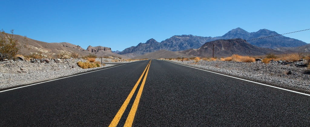 Long road with no one around, mountains in the background
